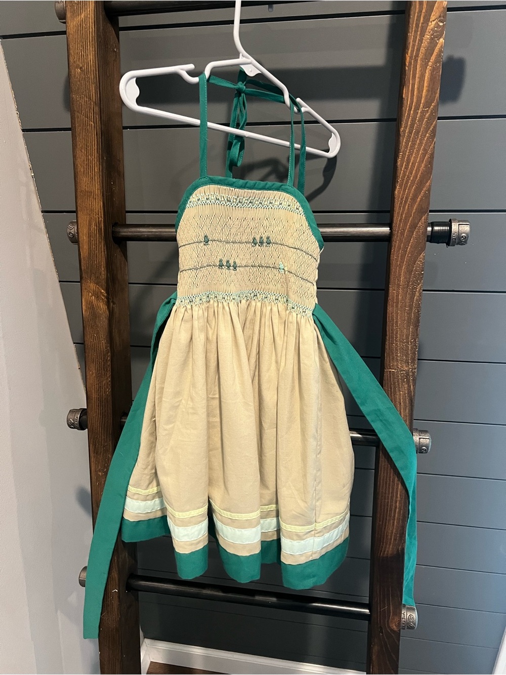 This is a Well Dressed Wolf "Bird on a Wire" smocked sundress in tan and green.